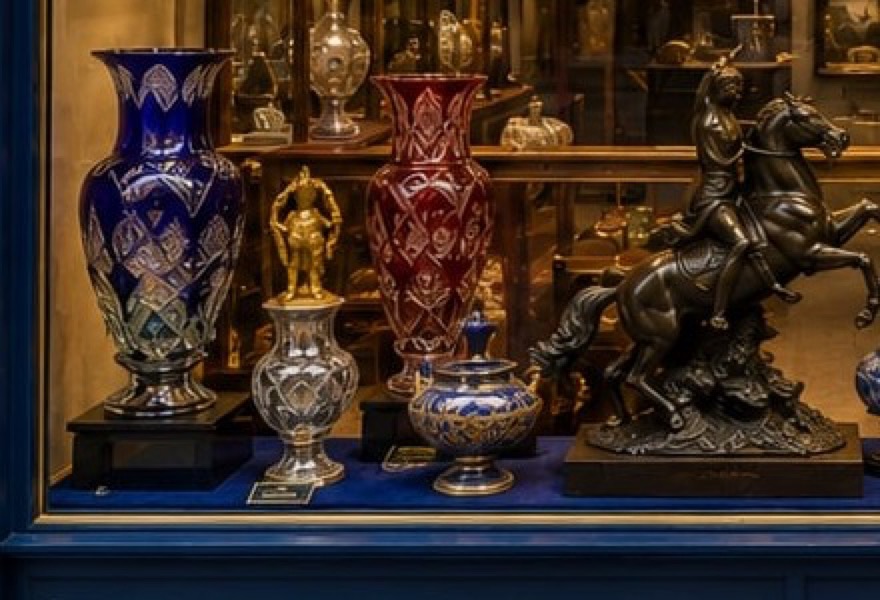 L'intérieur de la galerie : vitrines d'acajou, argenterie, tableaux anciens sous un éclairage chaud